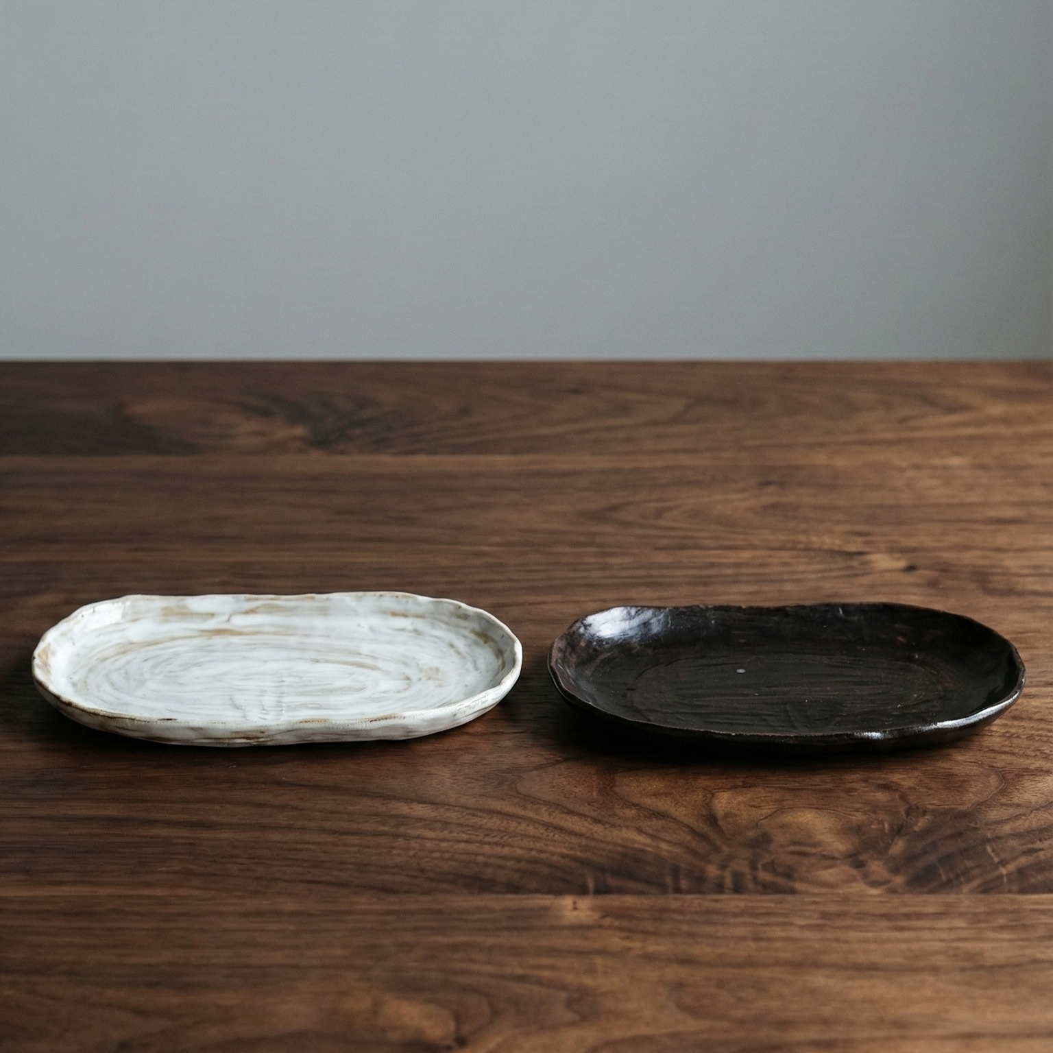 Two ceramic plates, one white and one black, on a wooden surface with a gray background.