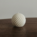 Textured spherical candle on a wooden surface with a neutral background