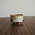 Small ceramic cup on a wooden surface with a neutral background