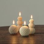 Set of four textured candles on a wooden surface with a neutral background
