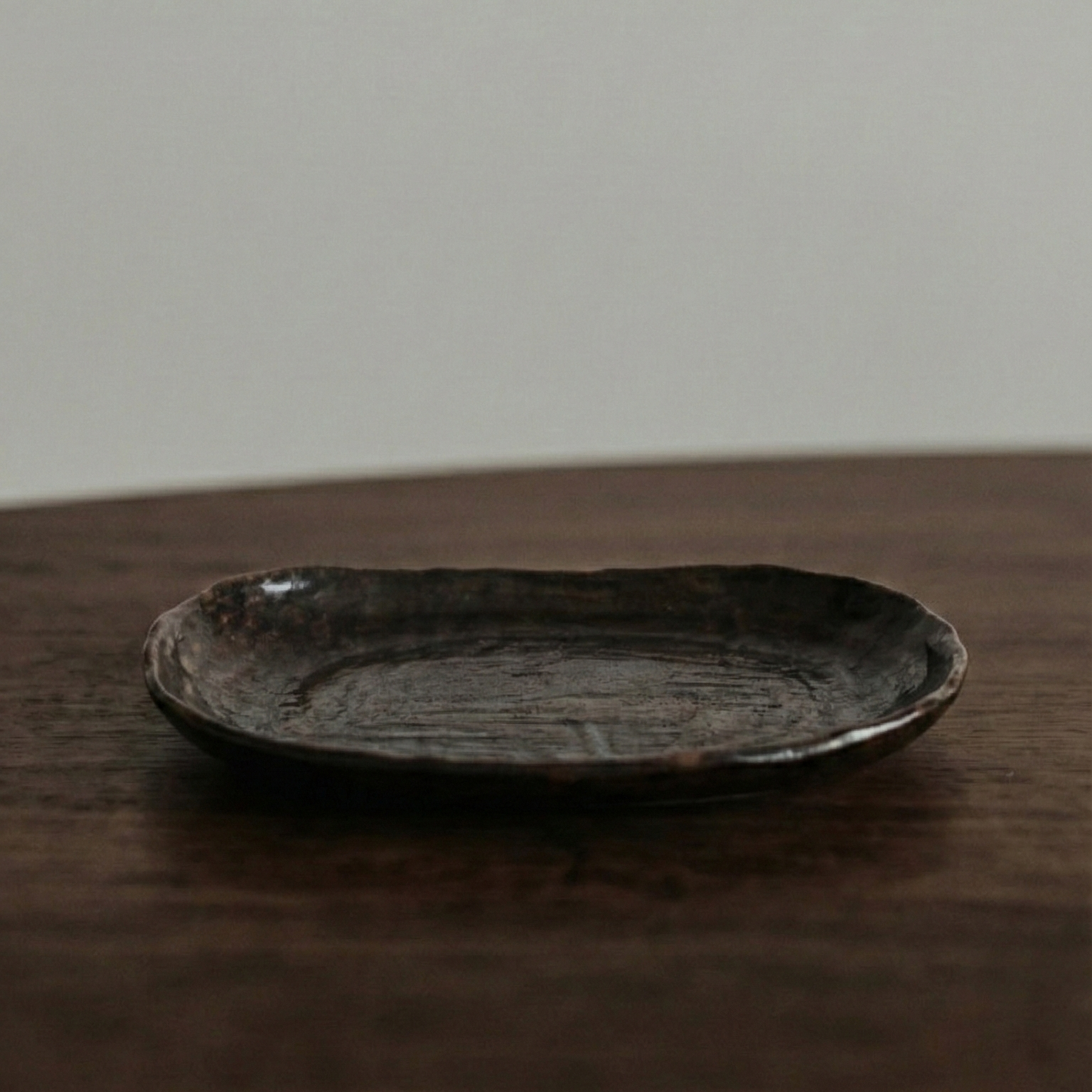 Black ceramic plate on a wooden surface with a plain background