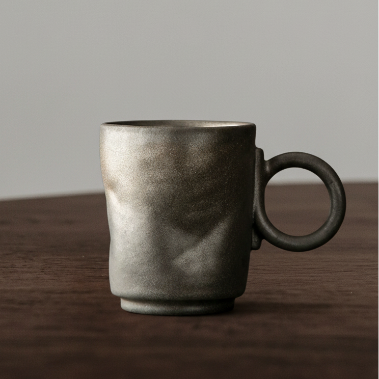 Dark gray ceramic mug on a wooden surface with a neutral background