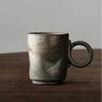 Dark gray ceramic mug on a wooden surface with a neutral background